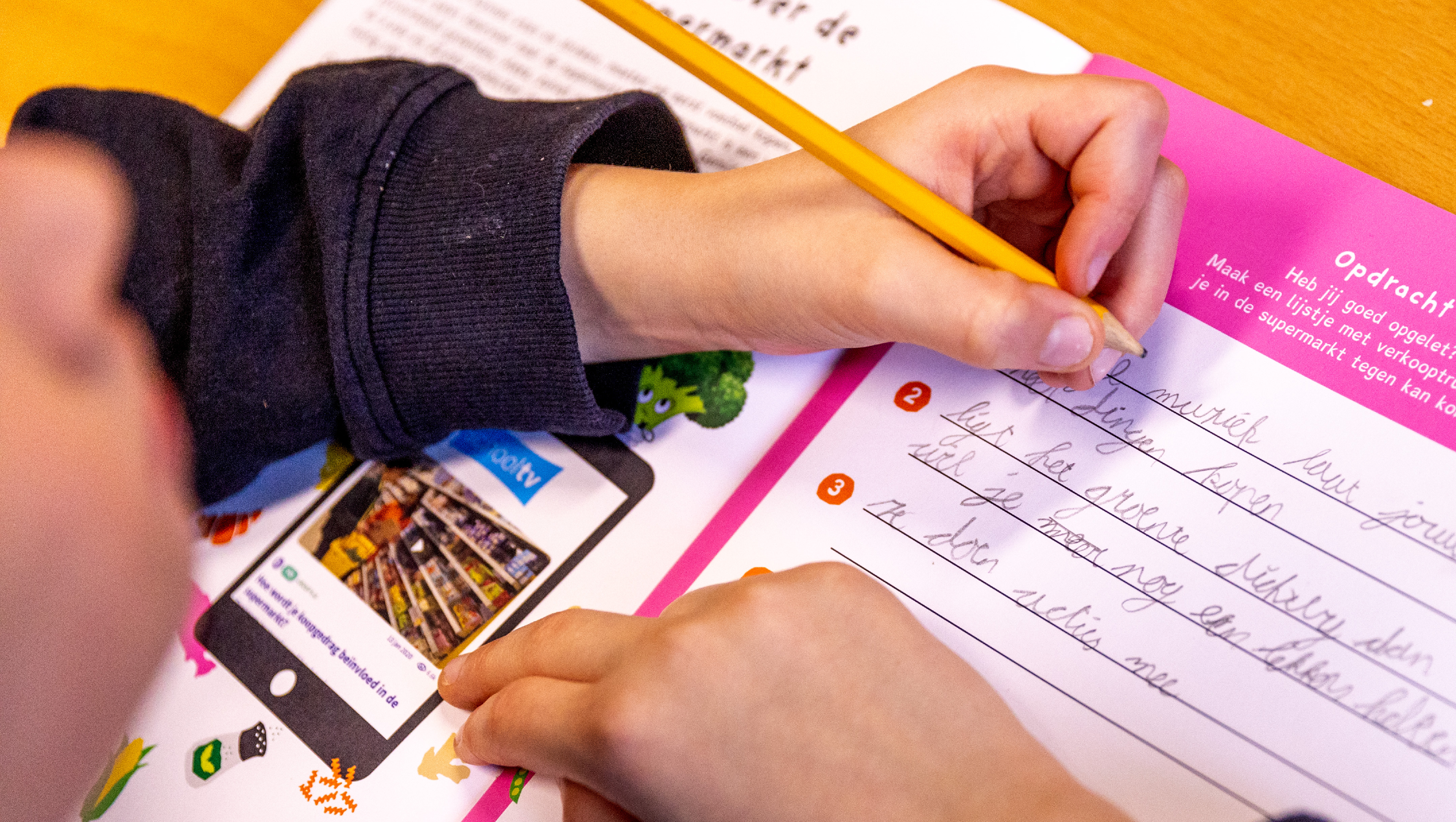 Een kind schrijft in zijn werkboek voor "Ik weet gezond"